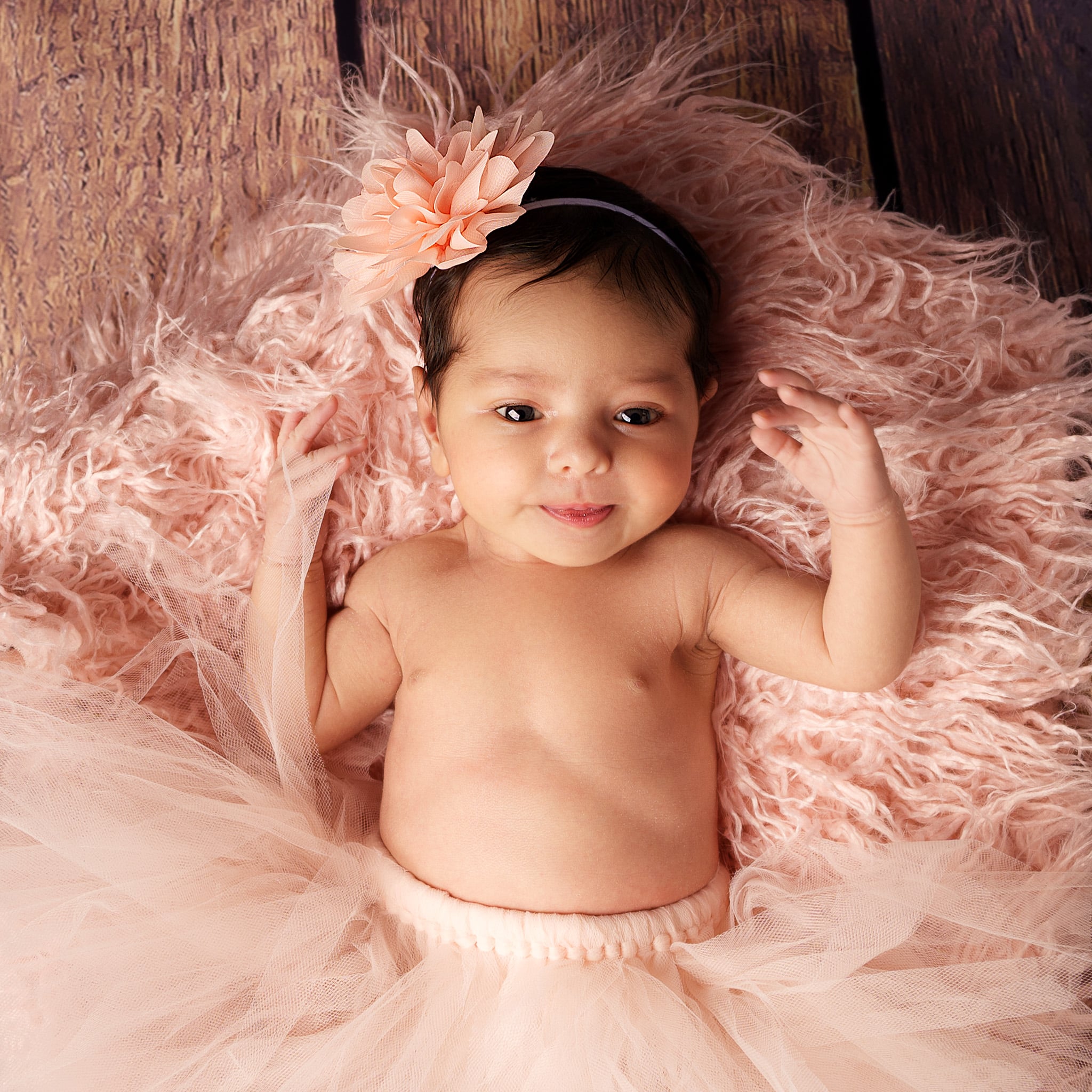 bébé nouveau-né sur fond rose avec fleur rose sur la tête