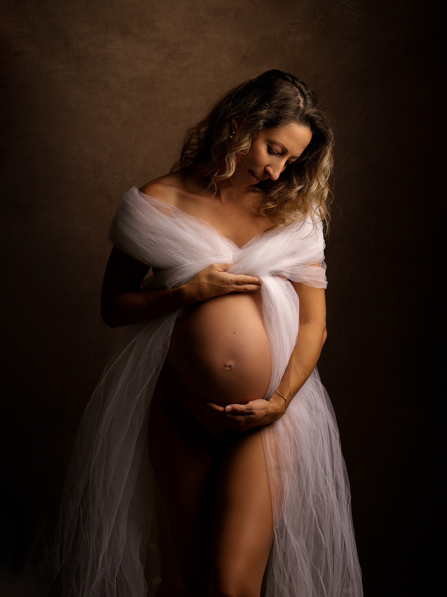 grossesse, femme enceinte dénudée qui regarde son ventre en souriant, avec un voile blanc sur les épaules